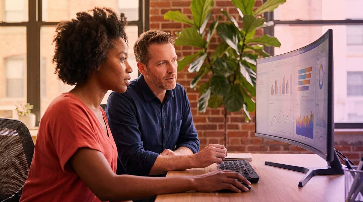 Two colleagues reviewing a digital marketing dashboard together in a bright collaborative workspace