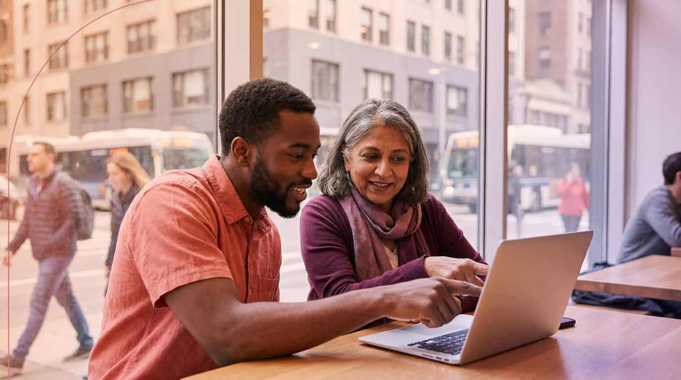 Two colleagues comparing supplier reviews on a laptop in a café